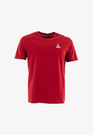 Rode katoenen t-shirt met korte mouwen en een ronde hals. Heeft een klein blauw en wit logo op de linkerborst. Gladde textuur.