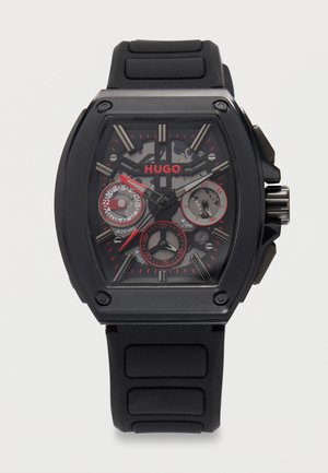 Fekete Hugo karóra téglalap alakú számlappal, piros részletekkel, három segédórával, amelyek 24 órás, napi és dátum mutatók, valamint fekete gumiszíjjal.