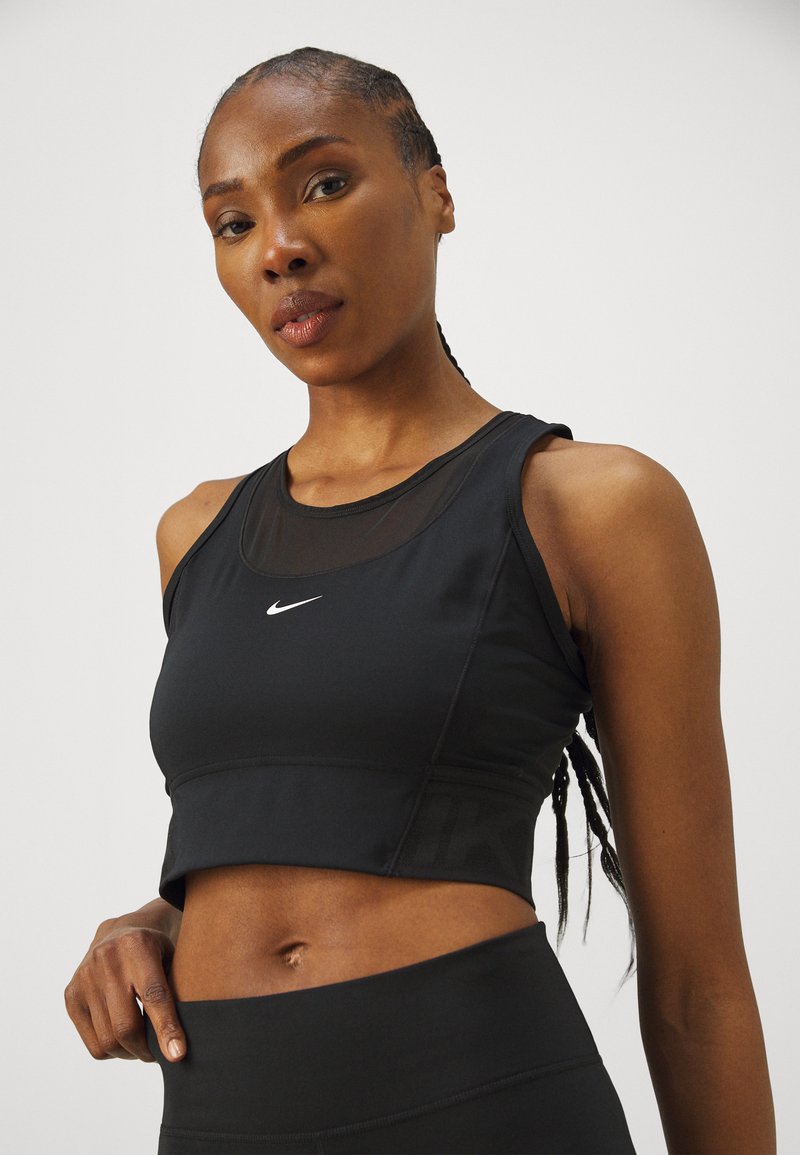 Crop top de sport noir avec un panneau en mesh, doté d'un col rond et d'un logo blanc. Fabriqué en matériau extensible, conçu pour le confort.