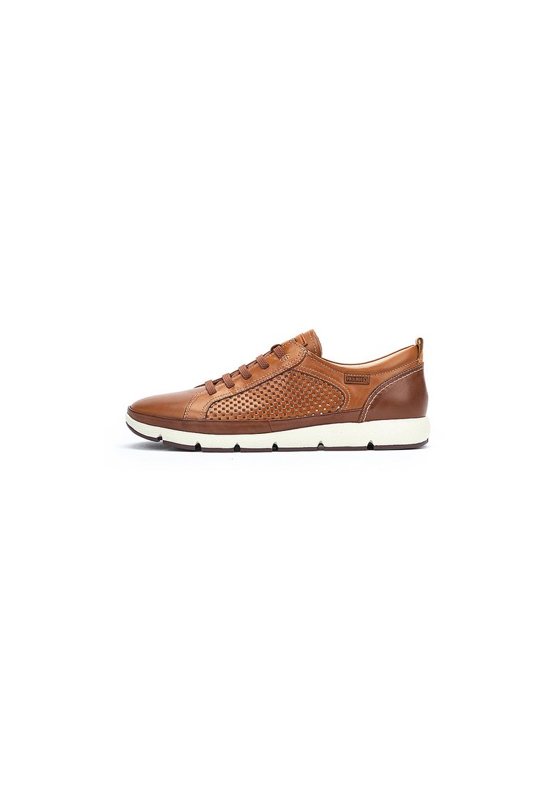 Zapatilla de cuero marrón con paneles laterales perforados, suela blanca plana y cordones redondos. Diseño curvado con una pestaña trasera para facilitar el calzado.