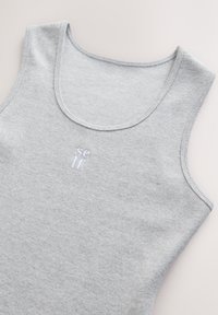 Szürke bordázott ujjatlan felső lekerekített nyakkivágással, finom fehér "self" hímzéssel. Puha tapintású és varrásmentes szegélyek a fokozott kényelemért.