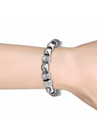 Bracciale d'argento con perline miste, inclusi motivi floreali e una sezione scintillante. Adagiato su un polso con una trama della pelle liscia.