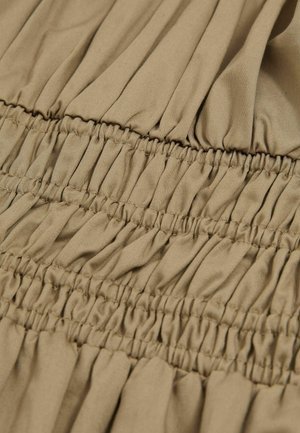 Tessuto beige con cuciture a sbuffo, caratterizzato da texture arricciata e pieghe verticali. Materiale morbido e leggero, con una finitura liscia.