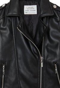 Veste en cuir noir avec des zips en argent, des boutons-pression et une finition texturée. Dotée d'une fermeture éclair frontale diagonale et de deux poches latérales zippées.