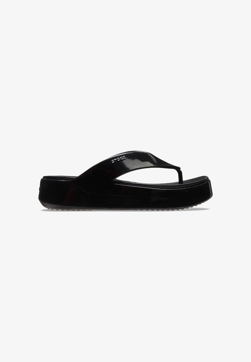 Sandale plateforme noire type tongs avec une finition brillante et une bride sur le dessus, vue de côté sur fond blanc.