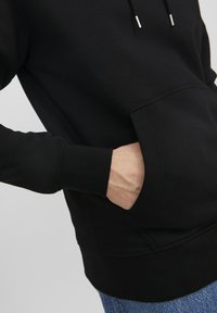 Zwart sweatshirt met een voorkant zak, trekkoord capuchon en geribbelde manchetten, gemaakt van zachte stof met een gladde textuur.