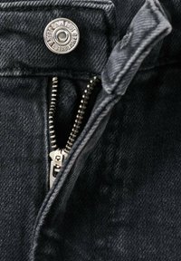 Jean en denim foncé avec un bouton argenté et une fermeture éclair. Le tissu présente une texture subtile avec des coutures fines le long des bords.