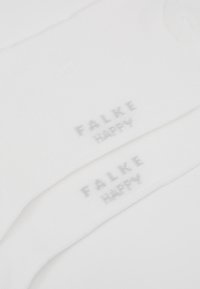 Bílé ponožky vyrobené z měkkého materiálu, s hladkým povrchem a světle šedým logem "FALKE HAPPY" tištěným na každé ponožce.