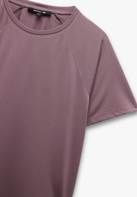 Kortærmet top i dæmpet mauve stof med rund halsudskæring og en tekstureret overflade med raglanærmer for en glat pasform.