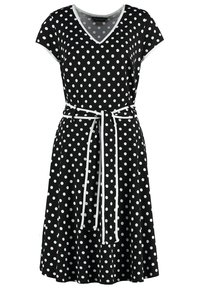 Svart klänning med vita prickar, korta ärmar, V-ringning och midja med bälte. Har vita detaljer och en utställd kjol.