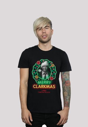 Black t-shirt featuring a graphic of a man in a Santa hat inside a Christmas wreath, text "MERRY CLARKMAS" in vibrant colors.