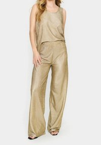 Złoty, żeberkowany zestaw składający się z topu na ramiączkach i spodni z szerokimi nogawkami. Gładka tekstura i luźny krój.