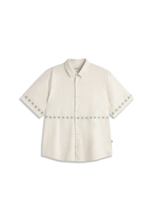 Chemise beige à manches courtes avec boutons, motifs en forme d’étoiles autour de la taille et des poignets, col étalé et coupe décontractée.