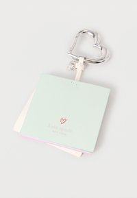Τετράδιο από δέρμα σε μέντα με ασημένιο μπρελόκ σε σχήμα καρδιάς. Διαθέτει κόκκινο λογότυπο καρδιάς και σελίδες στοιβαγμένες σε απαλές αποχρώσεις.