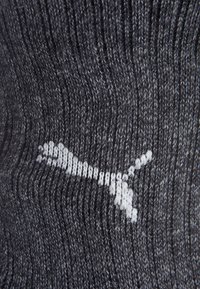 Ciemnoszara dziana tkanina z białym logo Pumy wyhaftowanym na środku.