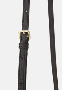 Correa sintética negra con un acabado texturizado y acentos brillantes, que cuenta con una hebilla de metal dorado para ajuste y sujeción.