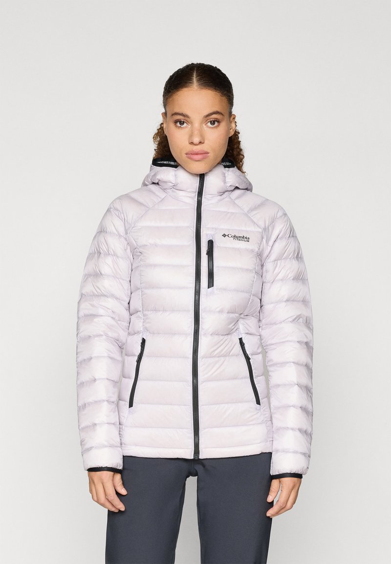 Világos lila puffertakaró, vízszintes steppeléssel, fekete cipzárokkal és kapucnival. Oldalsó zsebekkel és mellzsebbel rendelkezik.