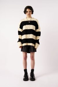 Juoda ir kreminė juostelėmis megzta stora megztinė su pynių raštu. Suderinta su juoda sijonu ir juodais batų lygiais kovos batais.