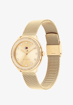 Gold-tone watch with a mesh bracelet, minimalist dial, crystal accents, and a logo. Round case with a smooth finish.