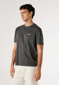 Donkergrijze T-shirt met korte mouwen in een zachte, lichte stof, voorzien van een klein wit logo op de borst en een label aan de zoom.