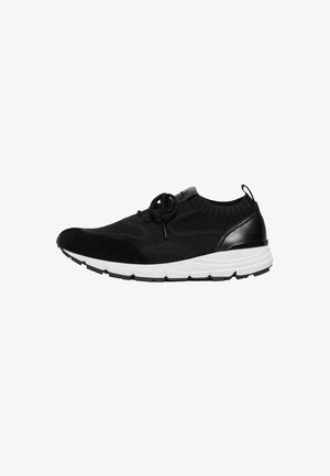 Chaussure de sport noire avec un dessus en maille, un capuchon en daim, des accents en cuir et une semelle blanche rembourrée avec une texture antidérapante.