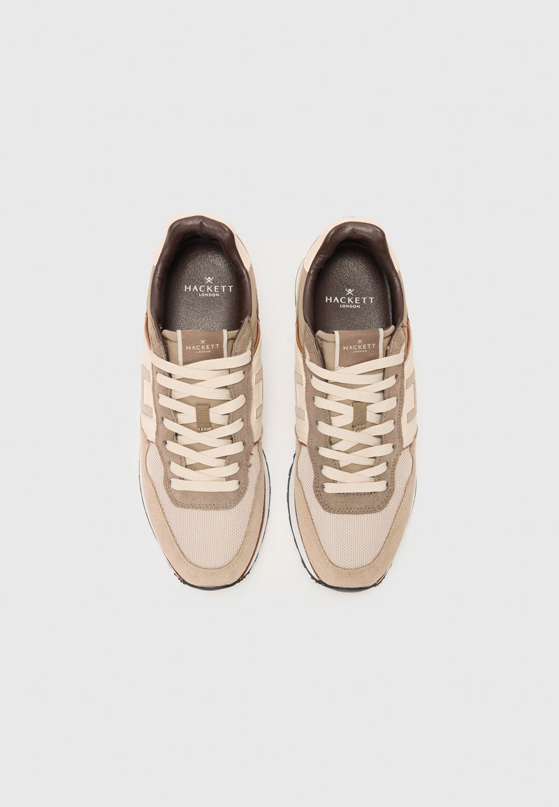 Une paire de baskets beige et marron de Hackett London avec des lacets crème, des détails en maille et en daim, vue de dessus sur un fond blanc.