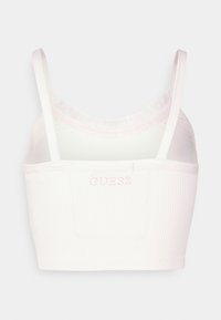 Bílý žebrovaný crop top s růžovou vyšívanou logem "GUESS". Má tenké ramínka a měkký, texturovaný povrch.