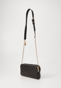 Černá kožená crossbody taška s hladkým povrchem, zipovým uzávěrem a odnímatelným řetízkem s pozlacenými akcenty.