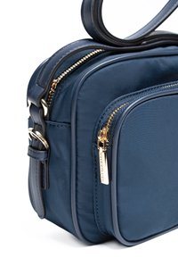 Borsa a spalla in nylon blu navy con hardware dorato, compartimenti con zip e una texture liscia. Presenta una singola tracolla regolabile.