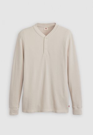 T-shirt henley à manches longues en tissu côtelé beige clair, avec un col en V, une patte de boutonnage à trois boutons et des manches à poignets. Étiquette logo rouge à l'ourlet.