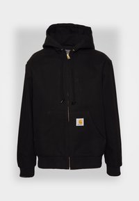 Schwarzer Kapuzenpullover mit Reißverschluss, Kordelzugkapuze, Fronttaschen, gerippten Bündchen und einem gelben Logoaufnäher auf der linken Tasche. Hergestellt aus strapazierfähigem Stoff.
