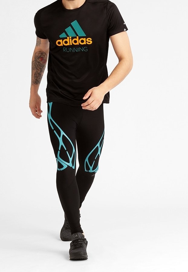 Black Adidas running t-shirt with green and orange logo, paired with black leggings featuring turquoise abstract patterns. Athletic shoes complete the outfit.