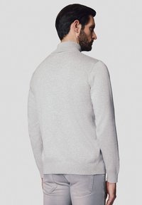 Jasnoszary sweter dzianinowy z wysokim kołnierzem, prążkowanymi mankietami i dołem, o gładkiej strukturze i dopasowanym kroju.