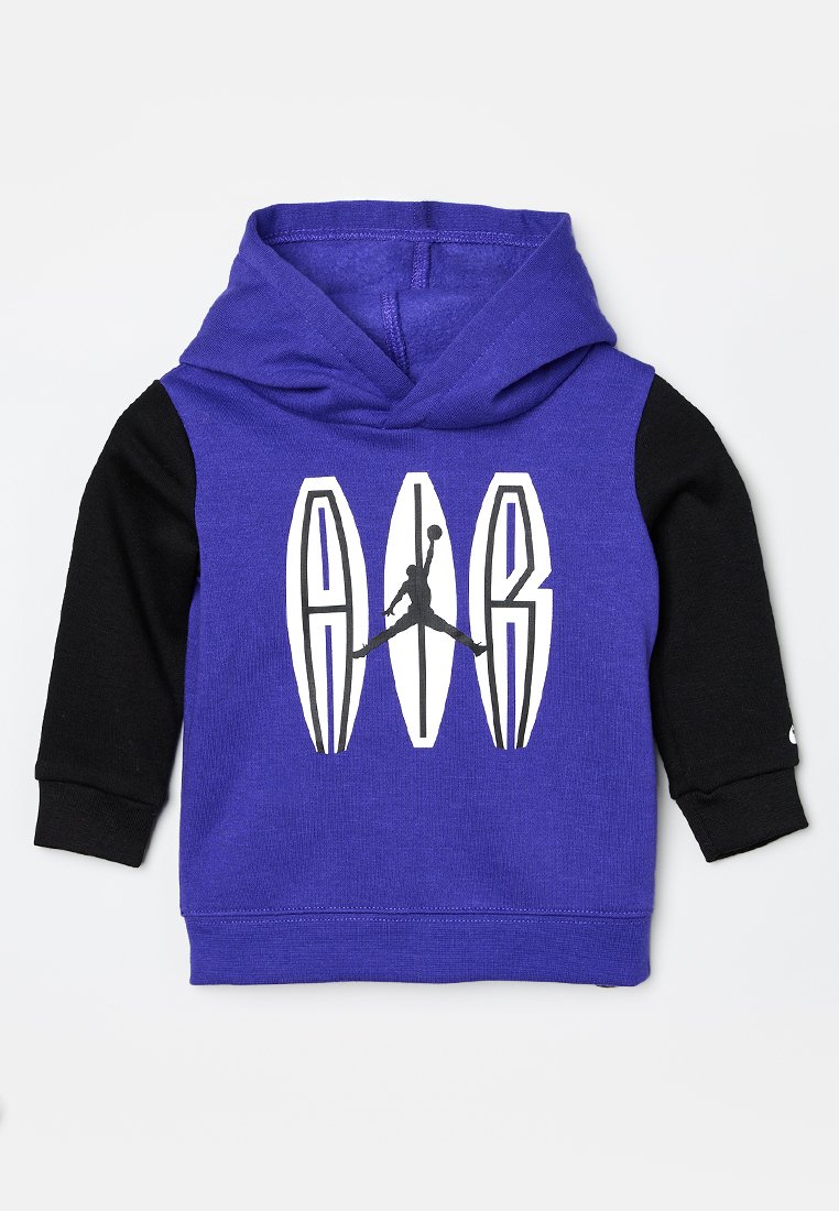Sudadera morada con mangas negras, que presenta un gran logo gráfico blanco en el frente. Fabricada con un tejido suave de acabado texturizado y con capucha ajustable.