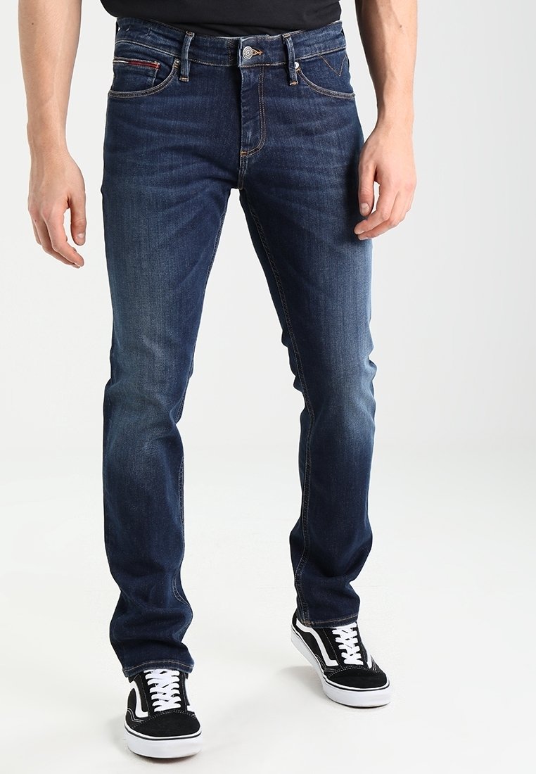 Mörkblå denimjeans med rak passform, som har en femficksdesign och gula sömmar, kombinerat med svarta och vita sneakers.
