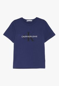 Camiseta de algodón azul marino con mangas cortas, que presenta un gran logo en blanco y negro de "CALVIN KLEIN JEANS" y un diseño estilizado "ck".