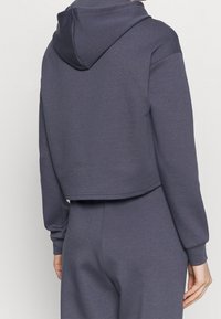Cropped hooded sweatshirt in dark gray, made of soft fabric, with long sleeves and a relaxed fit, featuring a structured hood and ribbed cuffs.