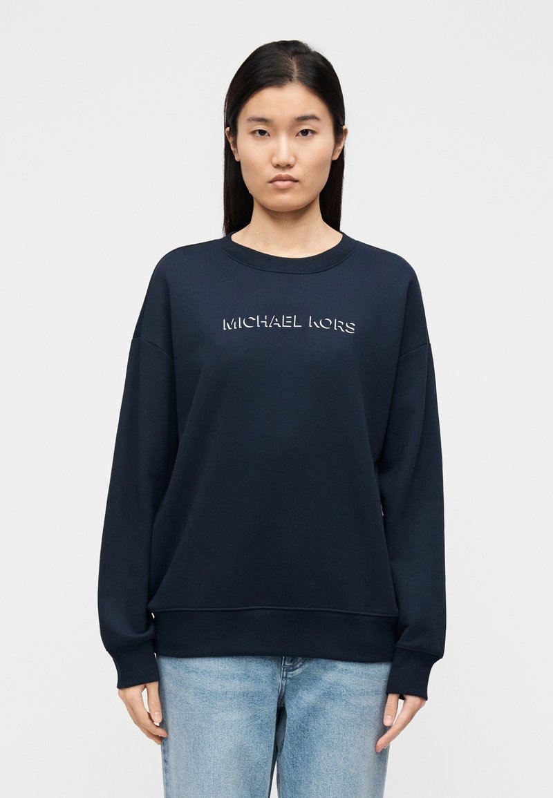 Μπλε σκούρο φούτερ από απαλό ύφασμα, με στρογγυλή λαιμόκοψη και χαμηλωμένους ώμους. Λογότυπο "MICHAEL KORS" σε αντίθετο χρώμα στο στήθος.