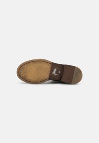 Sola de sapato de couro castanho com uma superfície texturizada, forma arredondada e detalhes cosidos. Apresenta um pequeno salto e marcações da marca.