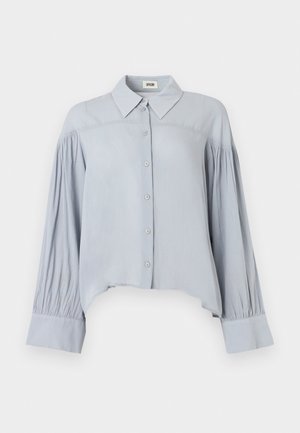 Lichtblauw overhemd met lange mouwen, knoopsluiting, puntige kraag, geplooide mouwen, brede manchetten en een asymmetrische zoom.
