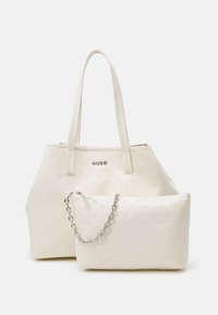 Hvid præget tote taske med to håndtag og en aftagelig pung med en sølv kæde. Glat, blød tekstur, minimalistisk design.