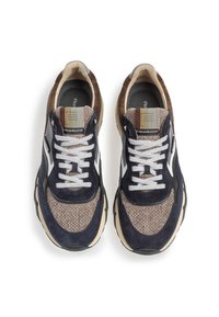 Marinbl å och bruna mockaskor med vävda textilpaneler, vita snören och en beige sula. Har en mönstrad etikett på plösen.