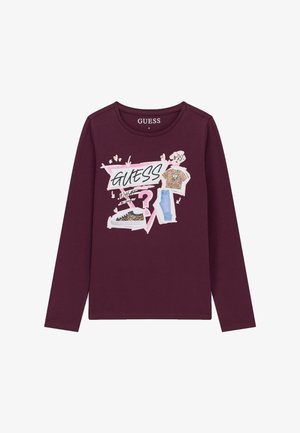 Chemise bordeaux à manches longues avec un graphisme rose et blanc représentant une chemise à imprimé léopard, un jean, une basket et le mot « GUESS » en lettres grasses.