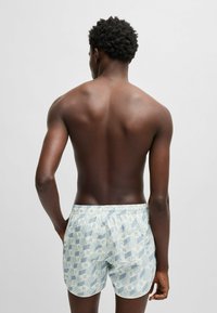 Bañador de color azul claro con estampado y cinturilla elástica. Presenta diseños geométricos en tonos blancos y azules. Textura de tela suave.