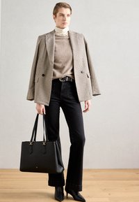 Must mustriba mustriba houndstooth ülikond, beež turtleneck-sviiter, mustad teksad, must käekott, kontsaga ankle-kingad, läikiva tekstuuriga.