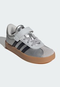 Silver and gray sneaker with a Velcro strap, mesh lining, rubber sole, and three dark stripes on the side, featuring a smooth, textured finish.