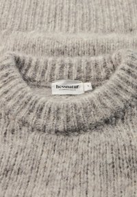 Hellgrauer Strickpullover mit gerippter Textur, breitem Ausschnitt und weichen Fasern. Enthält ein Etikett mit "hessnatur" und Größe S.