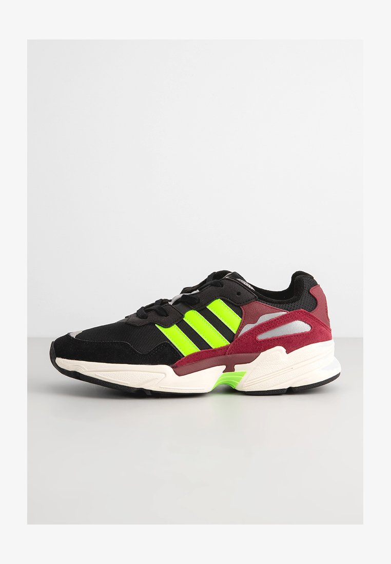 Chaussure de sport noire et bordeaux avec des accents en néon vert, présentant un dessus texturé, trois bandes et un design de semelle rembourrée.