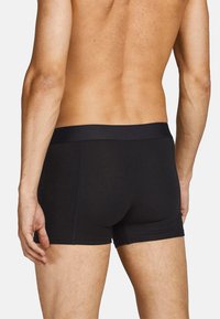 Schwarze Stretch-Boxershorts mit einem glatten Bund, enganliegendem Design und einer weichen Textur, die eine minimalistische Ästhetik ausstrahlen.