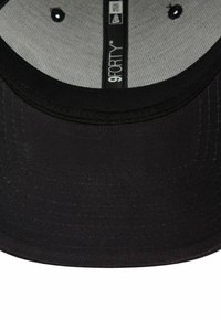 Czarna czapka bejsbolowa z zaokrąglonym daszkiem, teksturowana tkanina, wewnętrzna szara podszewka oraz naszywka "9FORTY" wszyta wewnątrz. Oferuje metalowe oczka.